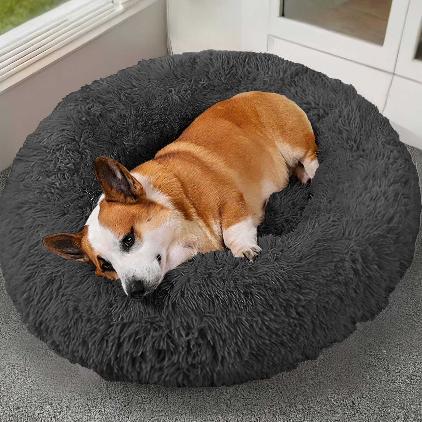 Dog lying on a fluffy gray pet bed indoors.