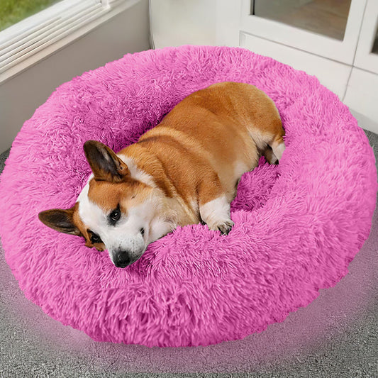 Pink calming plush pet bed with raised rim and ultra-soft cushion for dogs and cats.